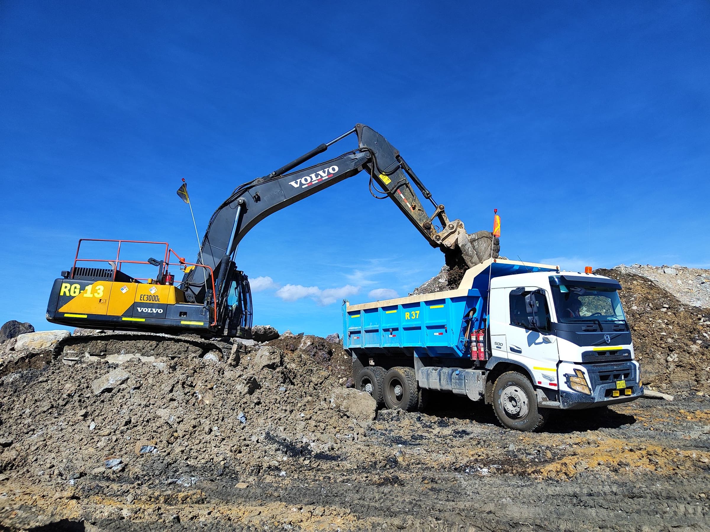 An excavator loading soil into a tipper truck on a sunny worksite