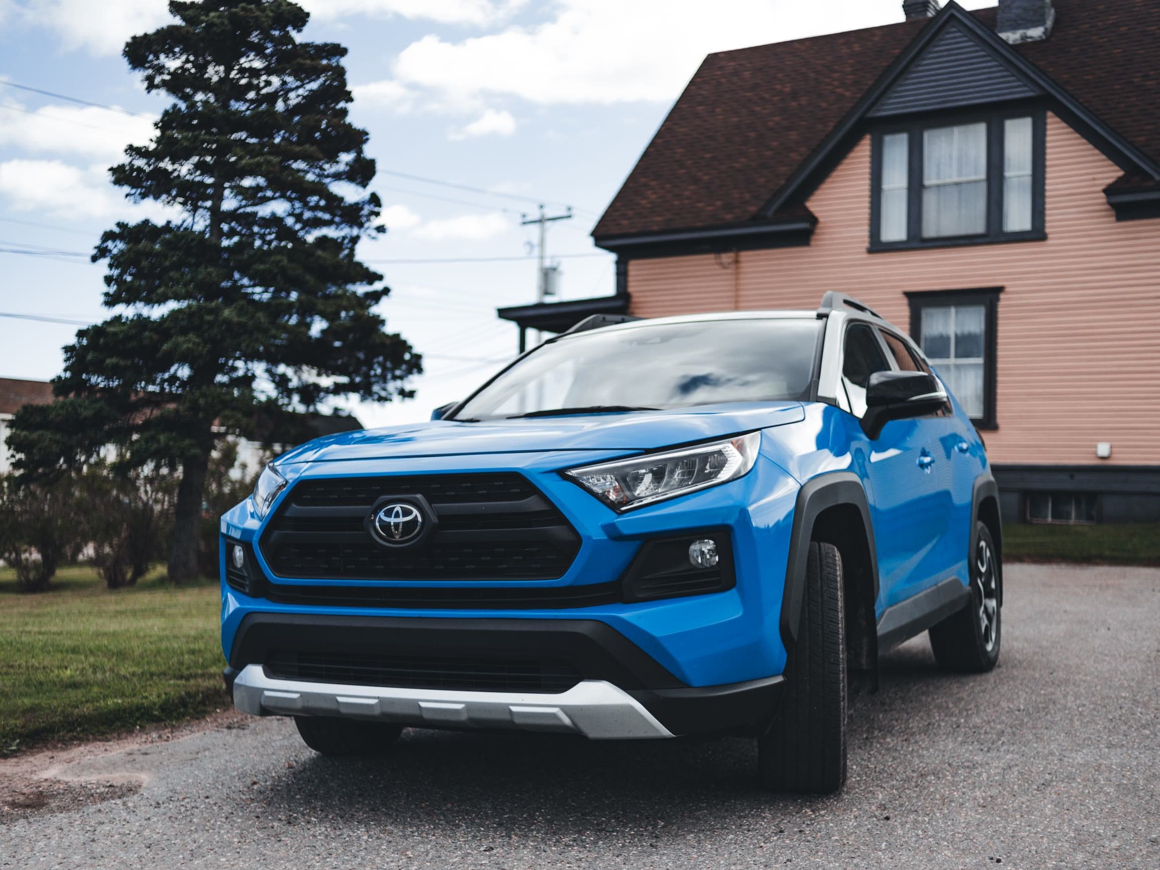 A blue Toyota RAV4 family SUV parked in the driveway of a house
