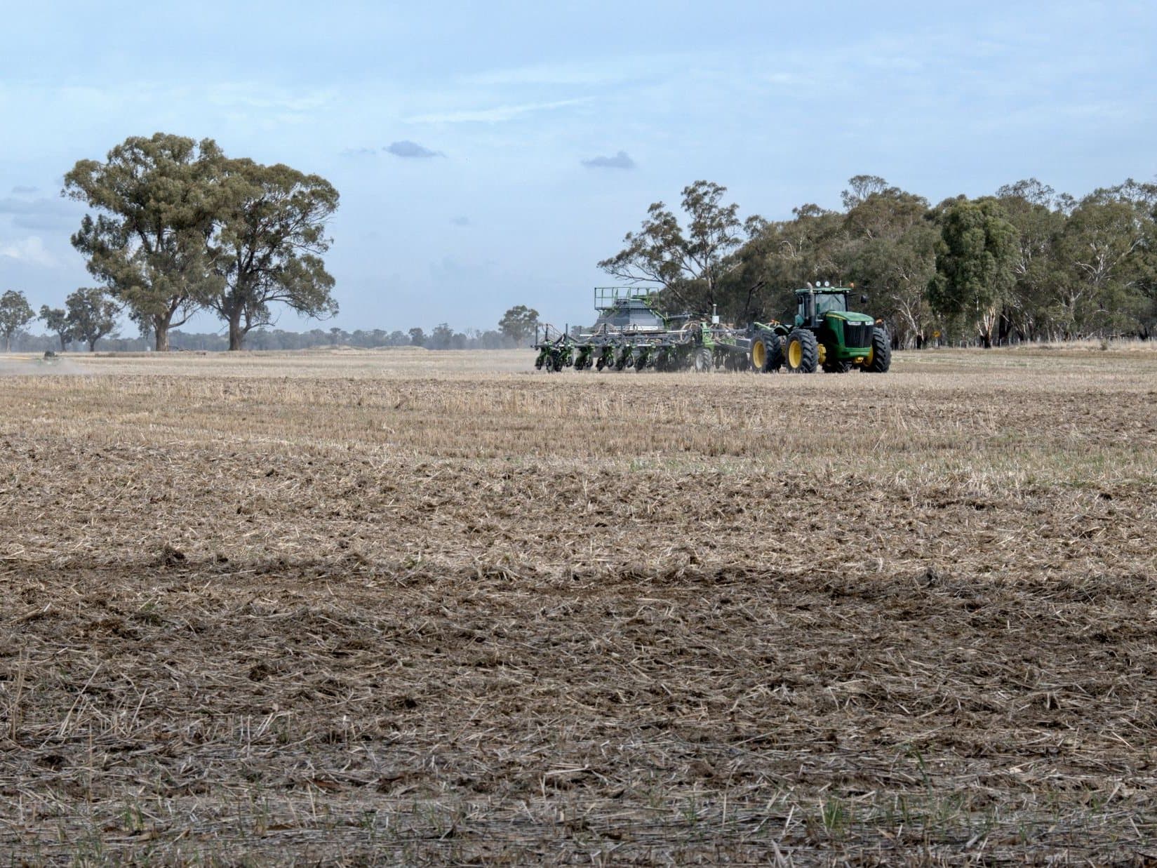 A tractor pulling an air seeder across a stubble paddock near Devenish, Victoria